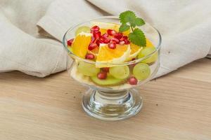 Fruit salad in a bowl on wooden background photo