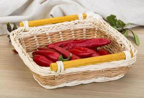 Chili peppers in a basket on wooden background photo