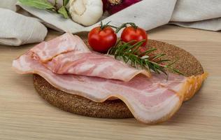 Bacon on wooden board and wooden background photo