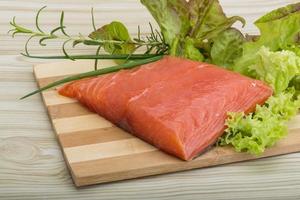 Salmon fillet on wooden board and wooden background photo