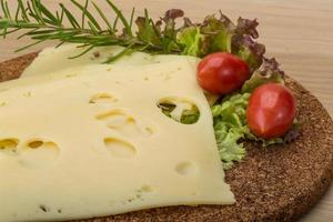 Maasdam cheese on wooden board and wooden background photo