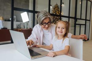 Child and granny looking at the camera with laptop photo