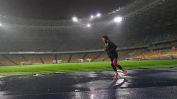 People go in for sports at night stadium in rainy weather photo