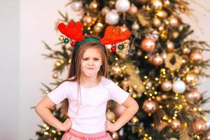 Portrait of little girl wearing deer christmas hat. Winter holidays and people concept. photo