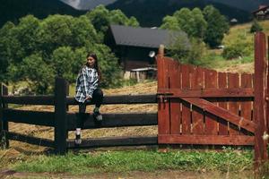 A young attractive Caucasian female sitting on a fence photo