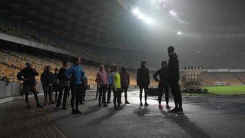 la gente practica deportes en el estadio nocturno cuando llueve foto