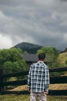 Guy by a fence of pasture enjoying nature. photo