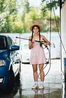 Woman with high pressure hose at car wash photo