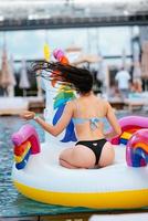 Woman on inflatable unicorn toy mattress float in pool. photo