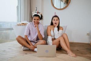 Young women on the bathroom floor looking at a camera photo