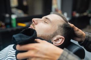 Barber preparing man face for shaving with hot towel in barber shop photo