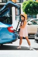 Woman packing her suitcase into luggage boot of the car. photo