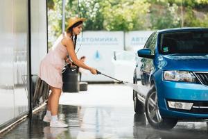 Brunette from a high-pressure hose washes the car photo