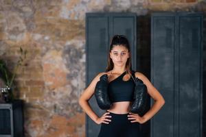 Sporty woman in sportswear posing on camera with boxing gloves. photo