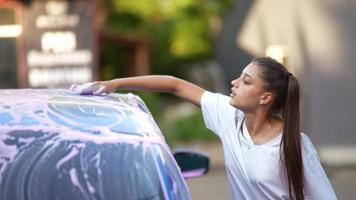 A young blonde woman washes her car photo