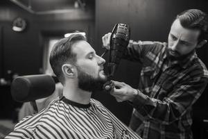 The master in the barbershop is styling the client's hair photo