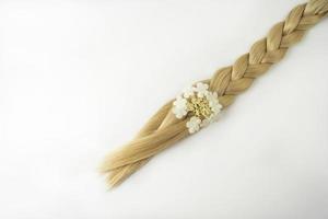 una trenza rubia con una flor blanca sobre ella sobre un fondo blanco foto