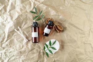 A face serum or essential oil with blank labels on them lying on a beige craft paper background photo