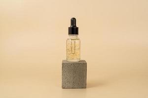 A face serum or essential oil with golden parts standing on a grey concrete podium photo