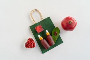 Red dropper bottles of pomegranate serum or oil for face and body lying on a white table photo