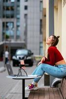 mujer bloguera en un café de verano transmitiendo en la calle. foto