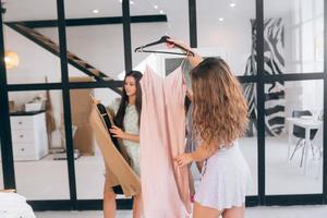 Two women choose and try on clothes at home photo