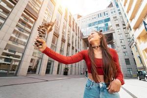 Young female blogger with smartphone streaming on the street. photo