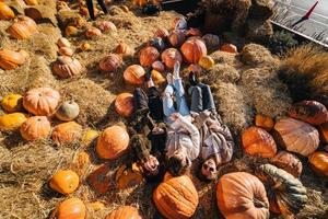 Young girls lie on haystacks among pumpkins. View from above photo