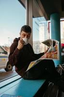 retrato de un hombre sentado en un café, leyendo periódicos y bebiendo café foto