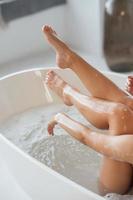 Cropped view of young woman lying in foamy bath photo