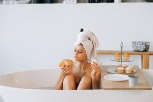 mujer de moda de lujo en la mañana toma el desayuno tumbado en el baño foto