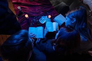 Two women and a guy are reading a mysterious books, close view photo