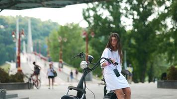 Girl sitting on a scooter and looks at smartphone photo