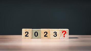 2023 number and red question mark on wooden cube block on wood table in room background. Next year planning concept. photo