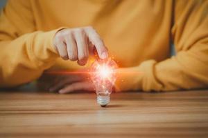 Man touching a bright light bulb. Ideas for presenting new ideas, inspiration in the work and innovation new beginning. photo