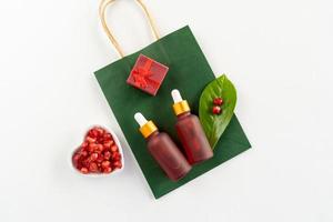 Red dropper bottles of pomegranate serum or oil for face and body lying on a white table photo