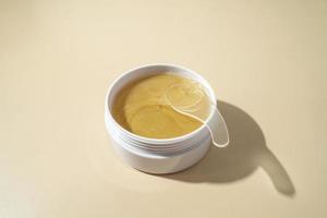 Golden antiaging eye patches with the snail extract lying on a beige background photo