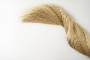 A strand of blonde hair lying on a white background photo