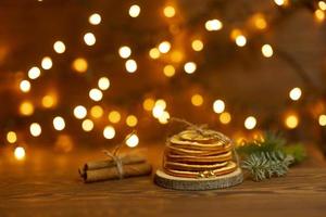 Two golden hearts lie nea the bunch of dried oranges with bokeh lights on the background photo