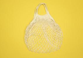 A white mesh empty bag lies on a yellow background photo