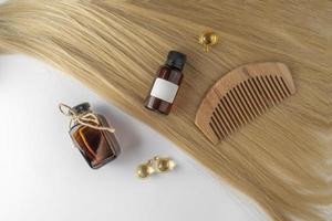 A hair care oil or serum in golden capsules lying on a strand of blond hair, product marketing mockup. A concept of hair care in a salon or at home photo