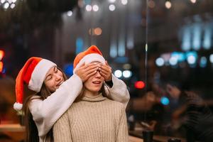 Portrait of happy cute young friends hugging each other at caffe. photo