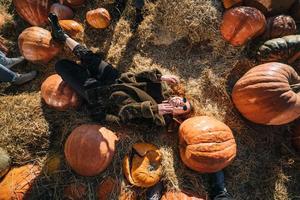 Young girl lie on haystacks among pumpkins. View from above photo