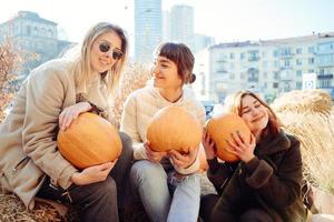 Girls holds pumpkins in hands on the background of the street. photo