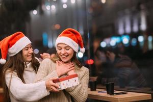 The girl gives a gift to her female friend in caffe photo