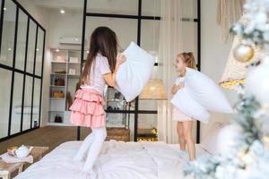 two little girls playing with pillows in bedroom photo