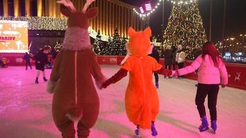 People enjoy ice skating in the street around Christmas tree in rink. photo