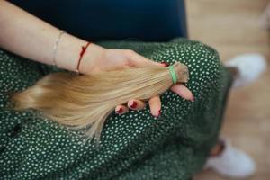 young woman holding her freshly cut long brown hair in pony-tails photo