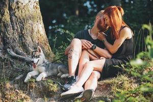 hermosa pareja sentada en un bosque cerca del árbol foto