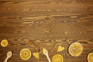 naranjas secas, un montón de canela y corazones dorados sobre una mesa de madera foto